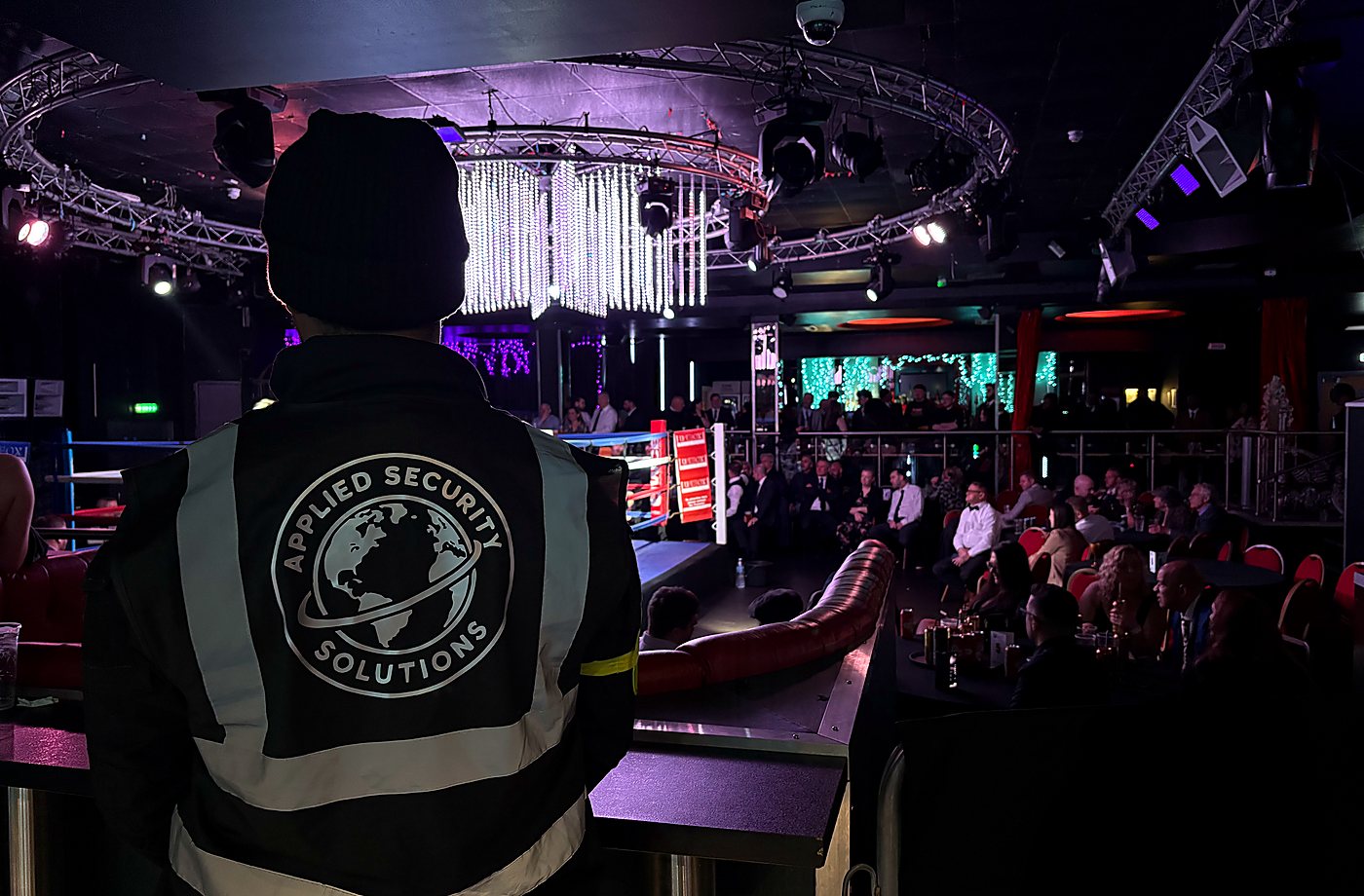 Applied Security Solutions officer overseeing a busy audience around a boxing ring